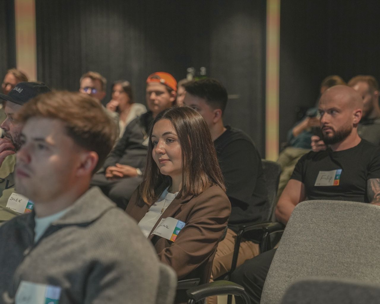 A Clay Club audience seated in rows, name badges on, watching a talk.